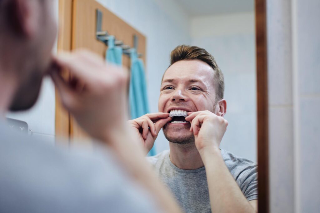 Man holding a clear aligner tray and smiling