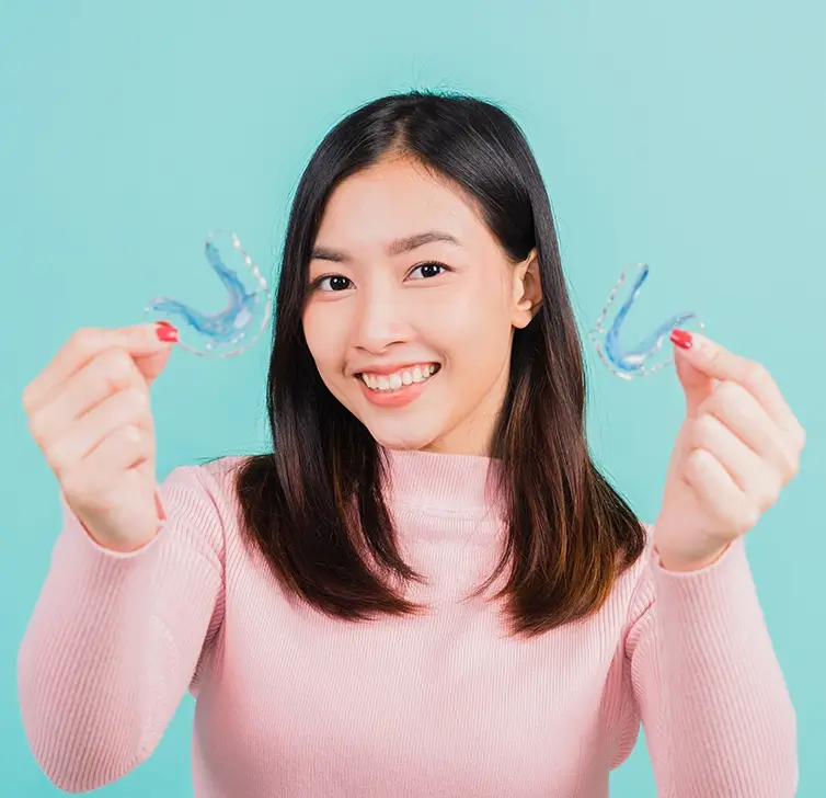 Patient holding a clear retainer after orthodontic treatment